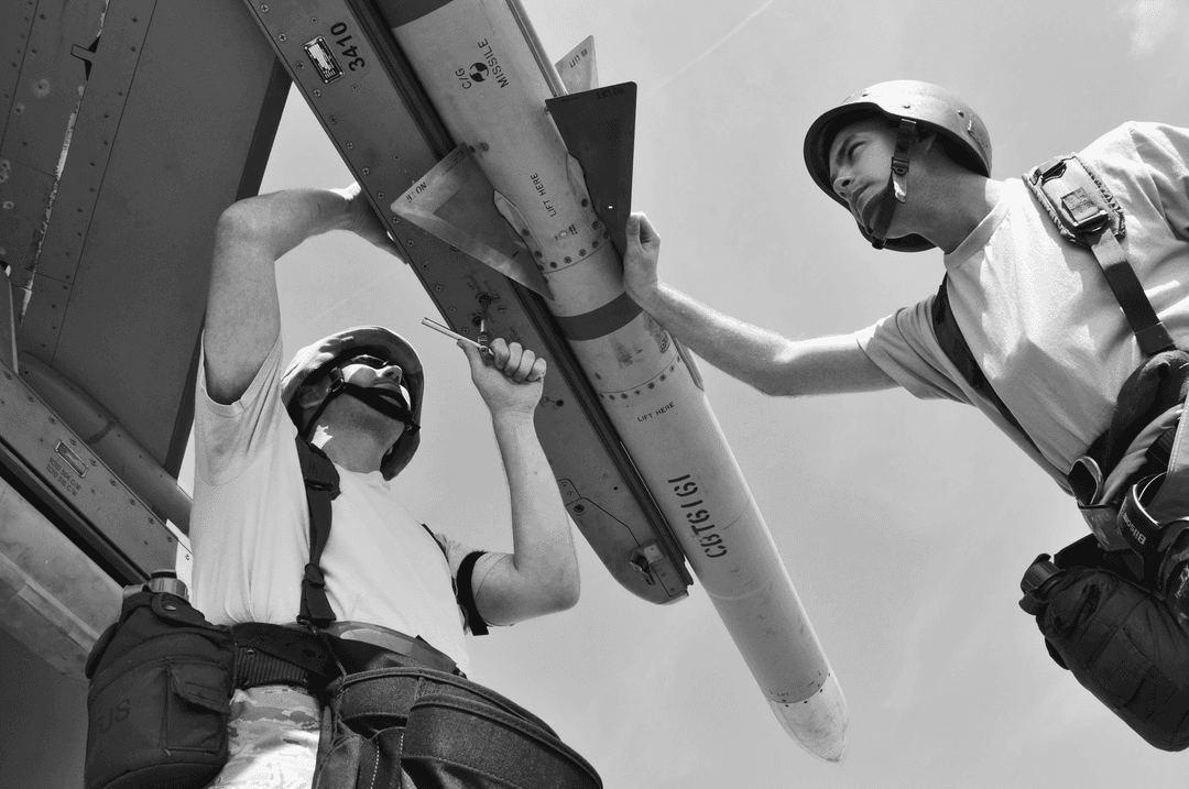 A couple of people wearing protective gear work on a drone.